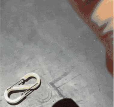 The carabiner being struck with a hammer on a concrete floor