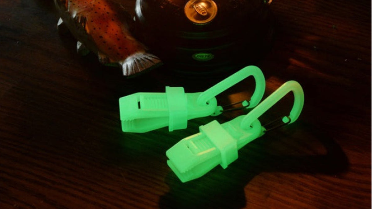 Glowing carabiner clips on a table by a lantern