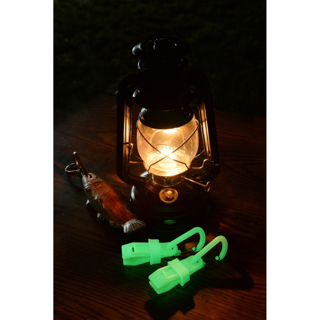 Glow-in-the-dark carabiner clips beside a lantern at night